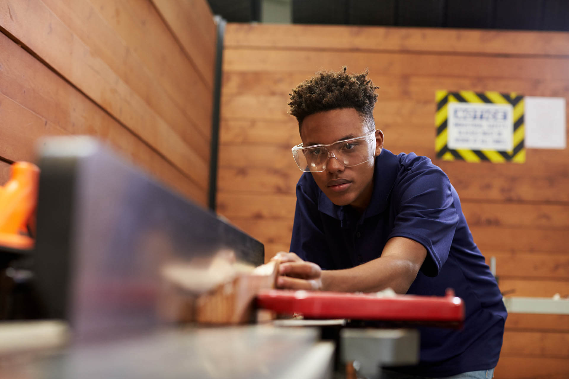 A young adult operating a wood cutting machine. 