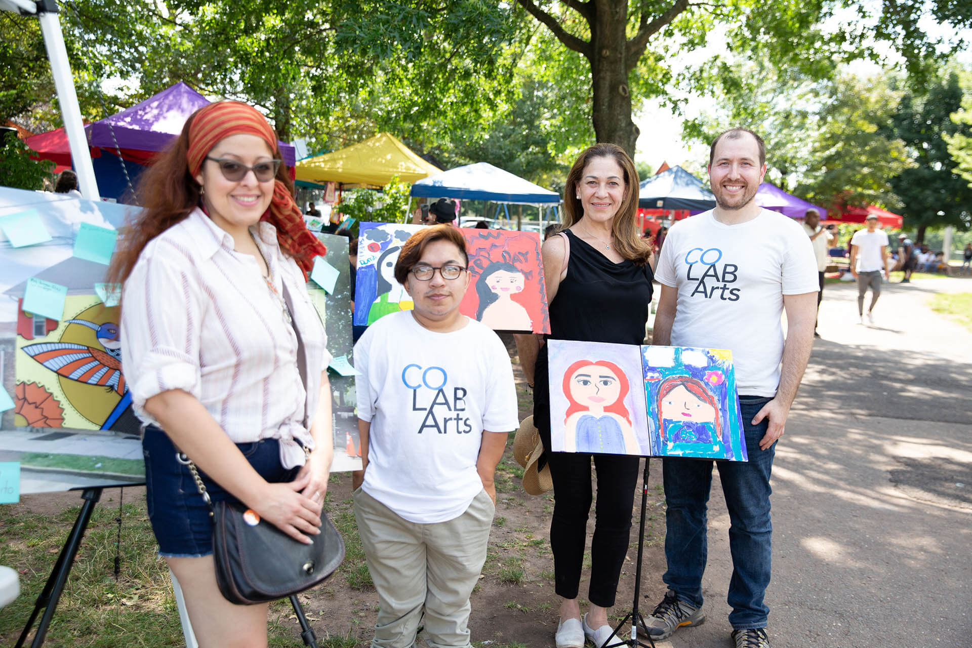 Artists standing infront of art pieces at an outside festival. 